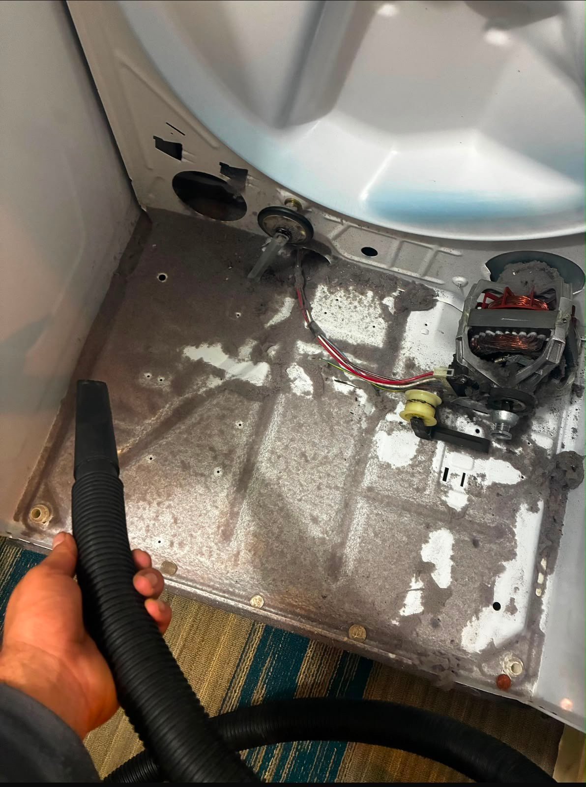 Vacuuming lint out of an opened dryer cabinet