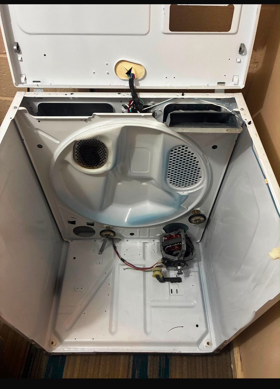 A dryer opened fully with the drum out and motor exposed