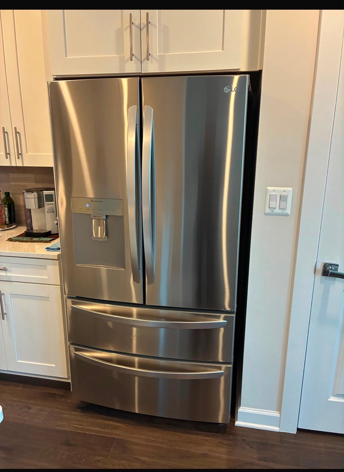 A stainless LG french-door refrigerator fitted into white cabinetry