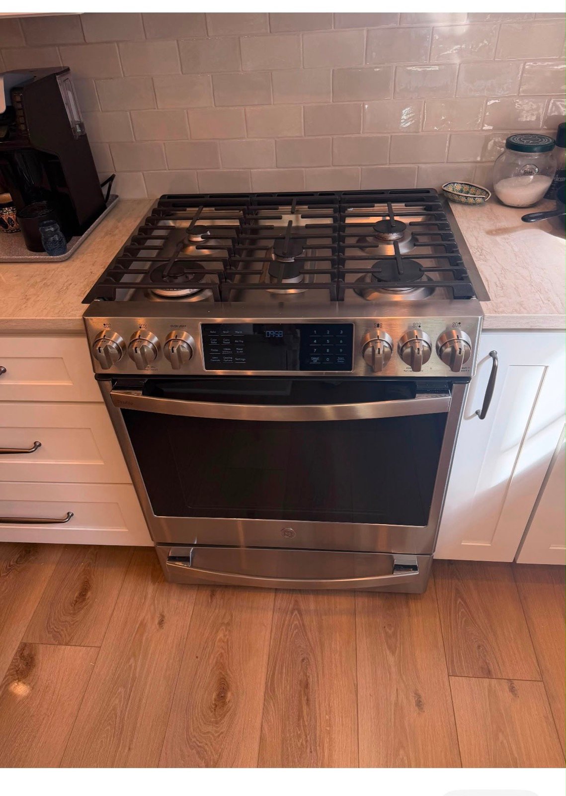 A stainless GE Profile gas range in a tiled kitchen