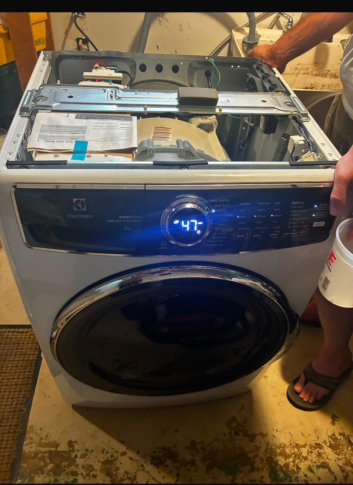 Front-load washer opened for repair, control panel lit